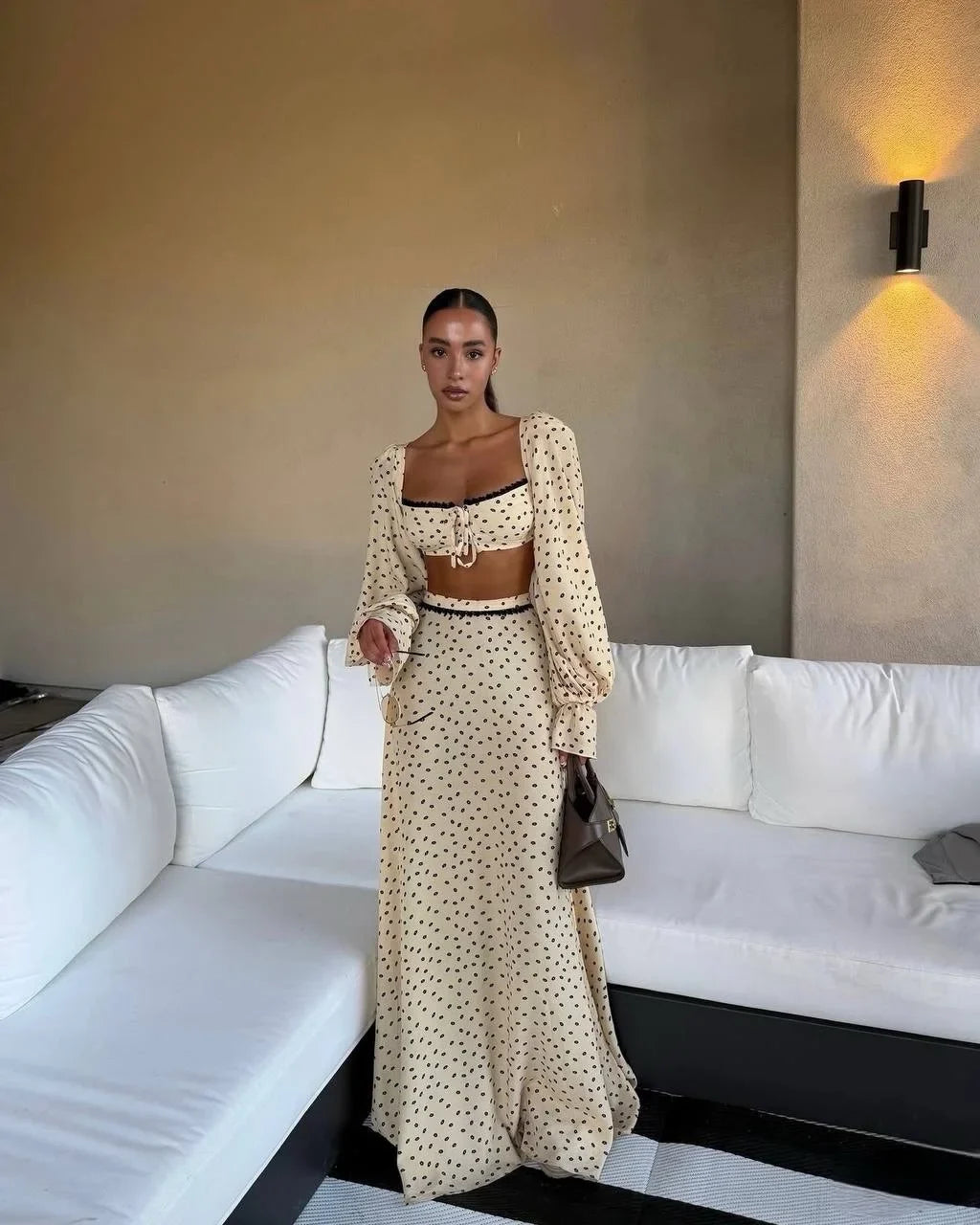 Woman in a polka dot outfit standing in a modern living room.