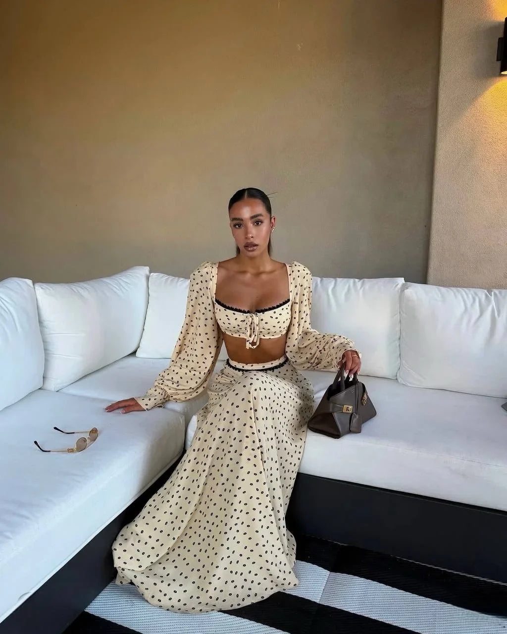 Woman in a polka dot outfit sitting on a white couch.